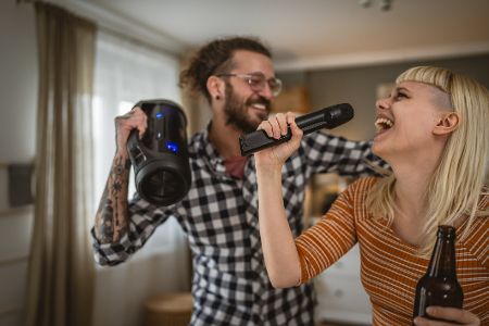 Mann und Frau singen und tanzen mit Mikrofon und Radio in der Hand