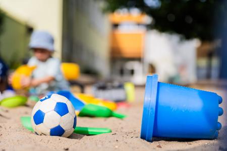 Ein Kind spielt in einem Sandkasten - wo haben dessen Eltern wohl Eimerchen, Schaufeln und den kleinen Ball gekauft, im Internet oder im Geschäft?