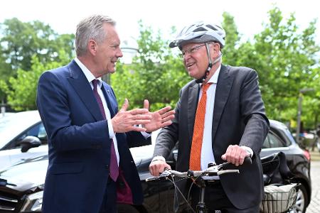 Mit Helm und Fahrrad kommt Stephan Weil (r) zur Wahl, bei der auch Christian Wulff zu Gast ist.