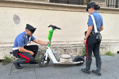 Zwei Carabinieri begutachten den Marmorsockel auf einem elektrischen Leihroller. Zwei Carabinieri begutachten den Marmorsockel auf einem elektrischen Leihroller.
