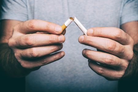 Männerhände zerbrechen Zigarette