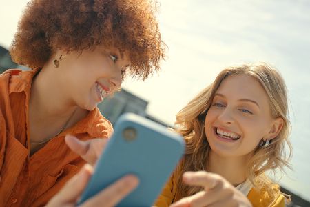 Zwei Frauen schauen auf ein Smartphone und freuen sich. Zwei Frauen schauen auf ein Smartphone und freuen sich.