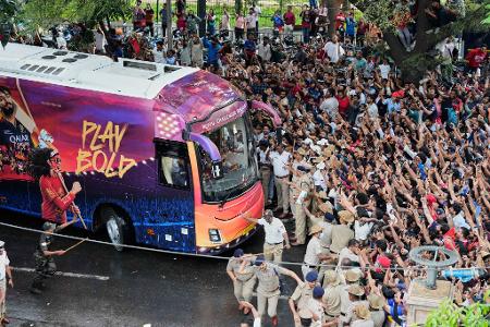 Kricket-Fans in Bengaluru jubeln ihrem Heimteam zu, das in einem Bus sitzt.