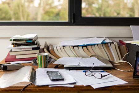 Unordentlicher Schreibtisch mit Büchern und Papieren