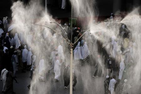 Kühlventilatoren besprühen muslimische Pilger mit Wasser, während sie zur symbolischen Steinigung des Teufels, dem letzten Ritus der jährlichen Hadsch, in Mina in der Nähe der heiligen Stadt Mekka Steine an Säulen werfen.