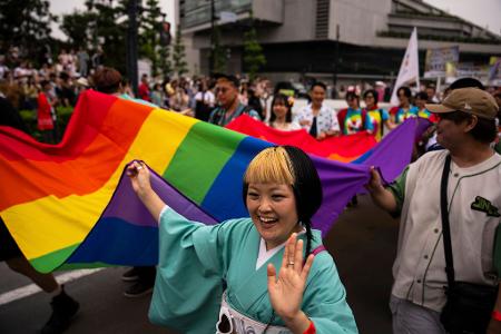 Pride-Marsch in Tokio: Menschen tragen eine Pride-Flagge, während sie am Pride-Marsch in Tokio teilnehmen.