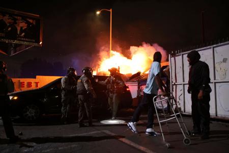 Ein Mann blickt auf ein Feuer, nachdem ihm die Strafverfolgungsbehörden während einer Demonstration aus einem Auto geholfen haben. Die Bundeseinwanderungsbehörden haben Operationen durchgeführt.