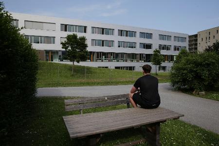 Marvin sitzt auf einem Tisch vor einem Schulgebäude und betet für die Opfer des Amoklaufs an einem Gymnasium. Ein 21-Jähriger hatte neun Menschen getötet und danach Suizid begangen.