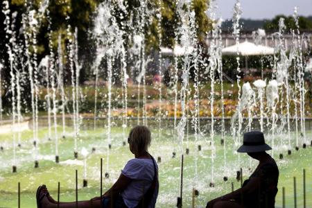 Zwei Frauen sitzen an einem Springbrunnen im egapark in Erfurt in Thüringen.