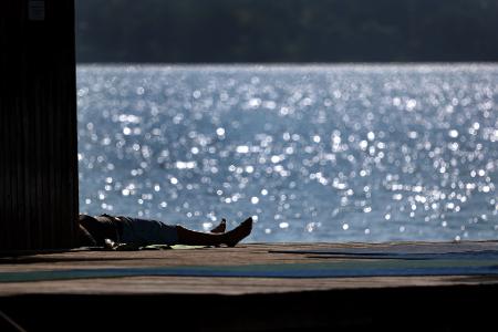 Ausflügler genießen auf dem Steg des Strandbades am Ammersee in Bayern den Sonnenschein.