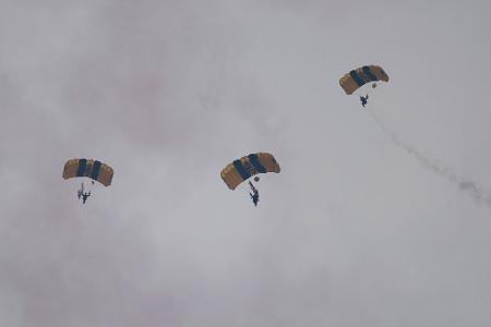 Am Himmel sind während der Parade Fallschirmspringer zu sehen. 