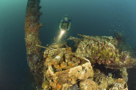 Taucher vor einem Wrack im Meer, auf dem alte Munition zu erkennen ist.