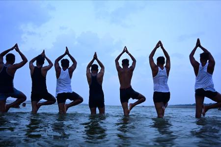 Menschen machen Yoga vor den Feierlichkeiten zum Internationalen Yoga-Tag in Prayagraj in Indien.