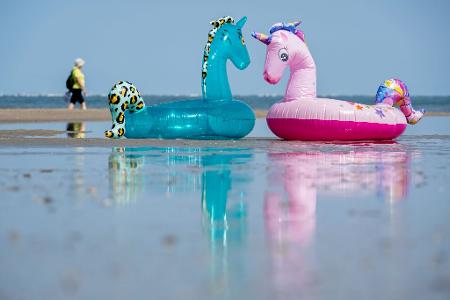 Echt heiß: Aufblasbare Schwimmtiere liegen bei schönstem Sommerwetter am Nordstrand der Insel Norderney.