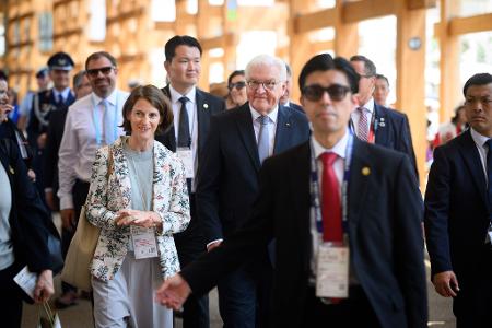 Bundespräsident Frank-Walter Steinmeier geht zusammen mit Melanie Saxinger (l), Generalkonsulin der Bundesrepublik Deutschland in Osaka-Kobe, und zahlreichen Sicherheitskräften und Personenschützern über das Gelände der EXPO 2025 Osaka.