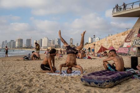 Während die gegenseitigen Angriffe zwischen Israel und dem Iran andauern, sind Menschen in Tel Aviv am Strand und genießen die Sonne und das Meer.