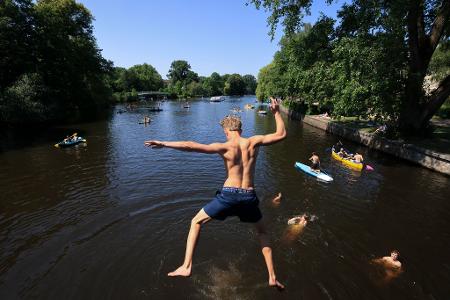 Sommerwetter in Hamburg: Ein junger Mann springt von einer Brücke in die Alster.