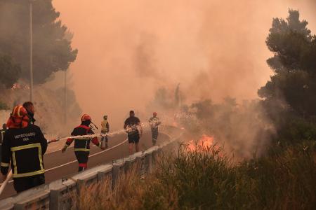 Feuerwehrleute löschen Brände neben einer Straße an der kroatischen Adria-Küste. Wald- und Vegetationsbrände wüten in der Region.