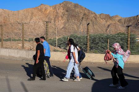 Menschen, hauptsächlich Iraner, die das Land aufgrund der israelischen Angriffe auf den Iran verlassen haben, gehen mit leichtem Gepäck am Grenzübergang an der armenisch-iranischen Grenze in der Nähe des Dorfes Agarak in der Gemeinde Meghri in der Provinz Syunik im Süden Armeniens.