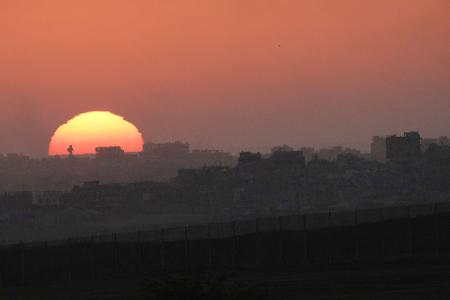 Die Sonne geht hinter zerstörten Gebäuden im nördlichen Gazastreifen nahe der Grenze zwischen Israel und Gaza im Süden Israels unter.