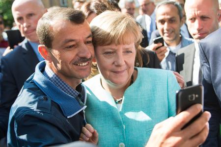 Bald zehn Jahre her: Angela Merkel (CDU) lässt sich nach dem Besuch einer Erstaufnahmeeinrichtung für Asylbewerber in Berlin-Spandau für ein Selfie zusammen mit einem Flüchtling fotografieren. (Archivbild) Bald zehn Jahre her: Angela Merkel (CDU) lässt sich nach dem Besuch einer Erstaufnahmeeinrichtung für Asylbewerber in Berlin-Spandau für ein Selfie zusammen mit einem Flüchtling fotografieren. (Archivbild)