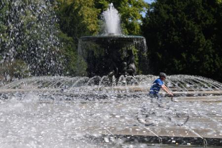 Ein Fahrradfahrer fährt in Dresden zwischen den Wasserfontänen der Brunnen 