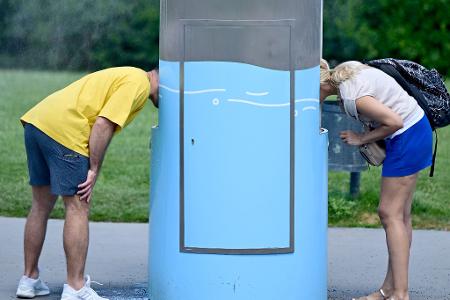 Hitze in Österreich: Zwei Personen trinken an einem Trinkbrunnen in Wien.