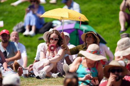 Zuschauer schützen sich gegen die Sonne und Hitze in Wimbledon.