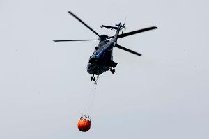 Ein Löschhubschrauber der Bundespolizei fliegt über dem Zeithainer Tagebau und nimmt Wasser auf, um den Waldbrand Gohrischheide zu bekämpfen.