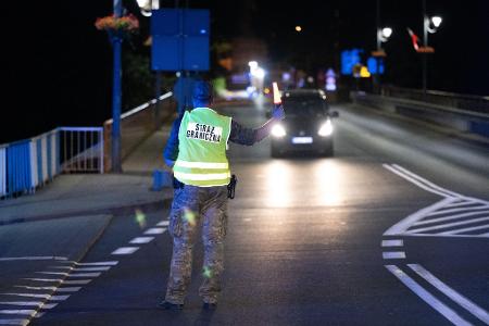 Ein polnischer Grenzschützer steht hinter der Stadtbrücke von Görlitz und winkt ein Fahrzeug zur Kontrolle raus. Polen hat vorübergehend die Grenzkontrollen an der deutsch-polnischen Grenze wieder aufgenommen. (Foto aktuell)