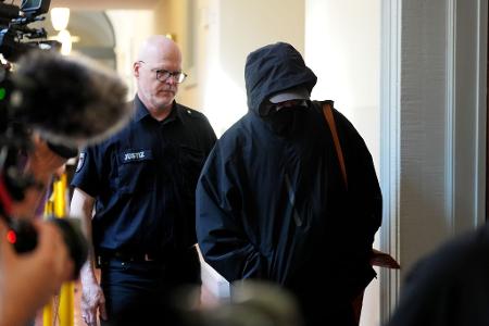 Ein Angeklagter wird von einem Polizisten zum Gerichtssaal begleitet. 