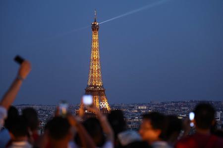 Paris im Sommer 2024 - besonders beliebt: Touristen fotografieren den Eiffelturm mit den Olympischen Ringen von der Terrasse des Triumphbogens. (Archivbild)