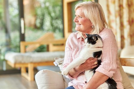 Ältere Frau kuschelt mit ihrer Katze