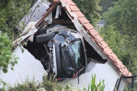 Das Auto liegt nach einem kurzen Flug seitlich in der Mauer einer Scheune.