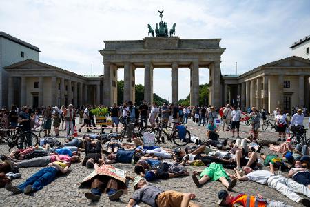 Teilnehmer einer Demonstration des Bündnisses "BaumEntscheid" liegen auf dem Boden auf dem Pariser Platz und simulieren einen Hitzetod.