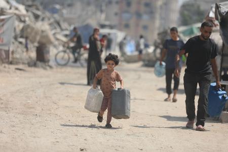Ein Kind trägt Kanister, um sich in Gaza Wasser von einem Tankwagen zu holen.