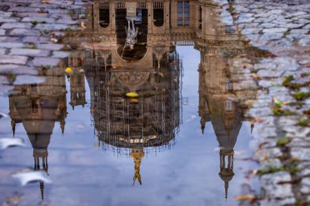 Das Schweriner Schloss spiegelt sich in einer Regenpfütze – graues, kühles und regnerisches Wetter zeigt den norddeutschen Sommer von seiner unfreundlichen Seite.