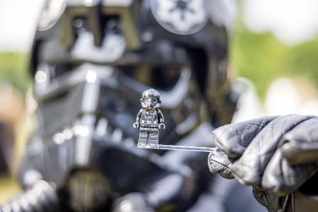 Ein Teilnehmer des Elbenwald Festivals, als Mitglied der Stormtroopers verkleidet, hält eine Figur seiner Rolle vor seinen Kopf.