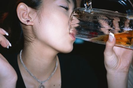 Junge Frau trinkt aus Bierglas