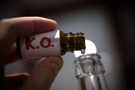 Mensch füllt aus Glasflakon K.o.-Tropfen in eine Flasche. Mensch füllt aus Glasflakon K.o.-Tropfen in eine Flasche.