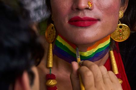 Eine Person bekommt den Hals in Regenbogenfarben für die Pride Parade in Kathmandu, Nepal bemalt.