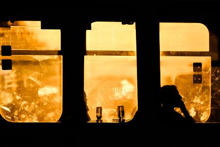 Die Silhouetten von Fahrgästen in einer Stadtbahn der Hannoverschen Verkehrsbetriebe Uestra zeichnen sich im Gegenlicht der aufgehenden Sonne ab.