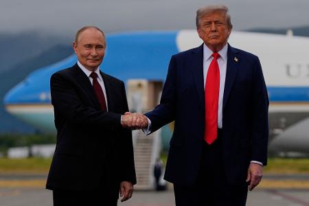 US-Präsident Donald Trump (r) und der russische Präsident Wladimir Putin geben sich auf dem Militärstützpunkt Joint Base Elmendorf-Richardson (in Alaska) die Hand.