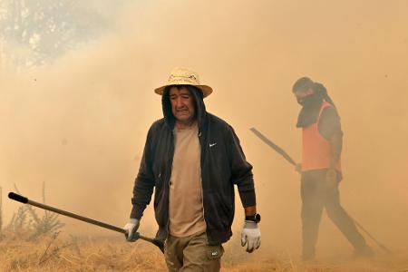 Menschen reagieren bei der Bekämpfung eines Waldbrandes in Veiga das Meas im Nordwesten Spaniens.