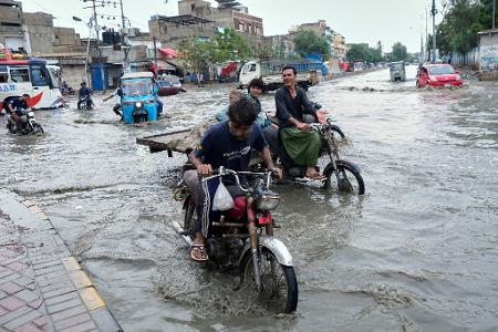 Nasse Füße bekommen diese Motorradfahrer nach schweren Regenfällen im pakistanischen Karachi.
