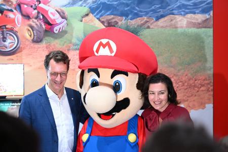 Beim Messerundgang über die Gamescom kam der Tross von Politikern auch beim Messestand von Nintendo vorbei, hier stehen NRW-Ministerpräsident Hendrik Wüst (CDU) und Bundesforschungsministerin Dorothee Bär (CSU) neben einer Mario-Plüschfigur.