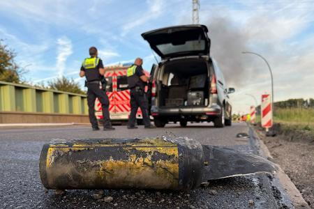 Polizisten stehen hinter einem Metallbehälter. Trümmerteile sollen bei dem Brand Hunderte Meter weit geflogen sein. 