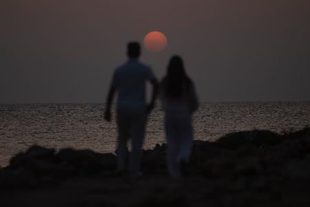 Ein Mann und eine Frau spazieren in der Nähe des Strandes Es Cargol in Santanyi auf Mallorca während des Sonnenuntergangs.