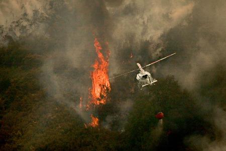 Ein Löschhubschrauber wirft Wasser über einem Feuer in der spanischen Provinz Ourense ab. Ein Löschhubschrauber wirft Wasser über einem Feuer in der spanischen Provinz Ourense ab.
