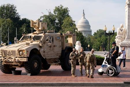 Mitglieder der Nationalgarde, die auf Anordnung von Präsident Trump in der US-Hauptstadt Washington sind, stehen neben einem gepanzerten Fahrzeug. 